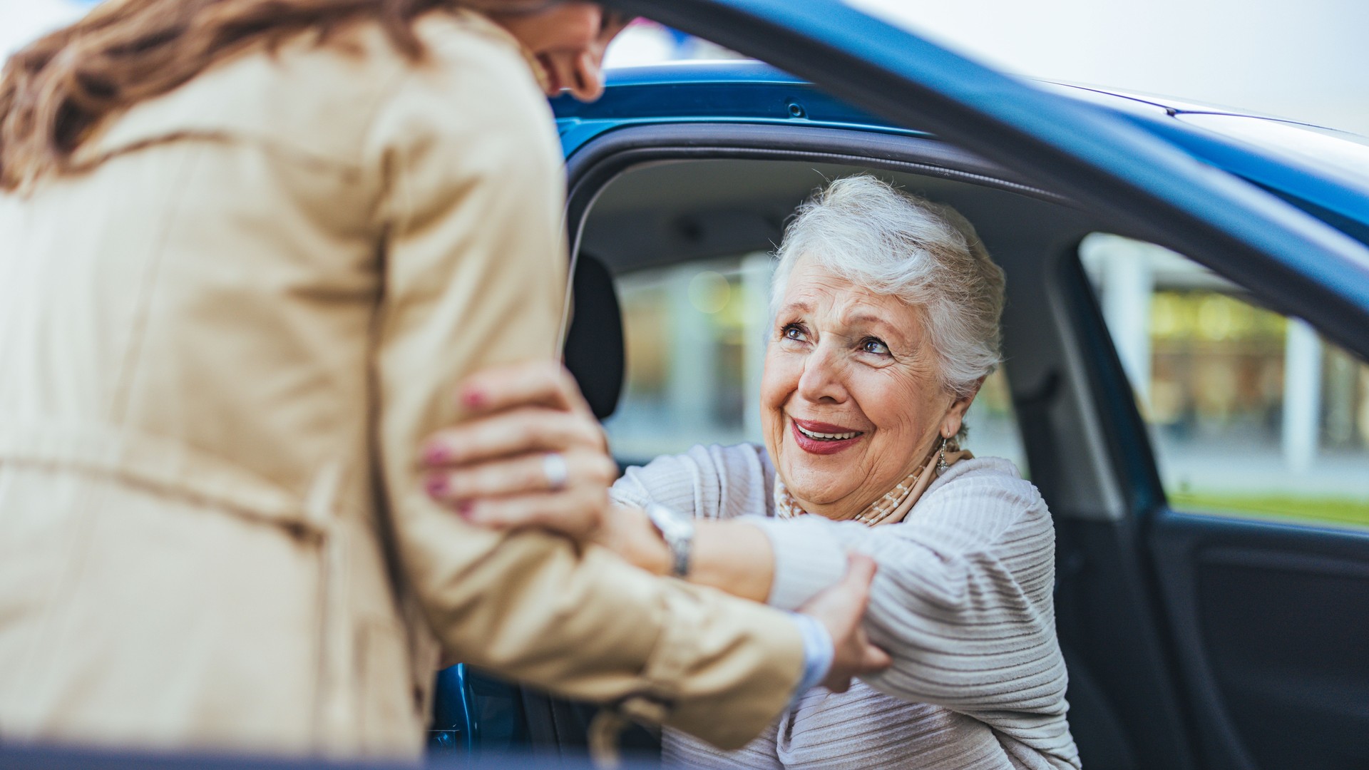Joyful Senior Woman Being Helped Out Of Car By A Friend